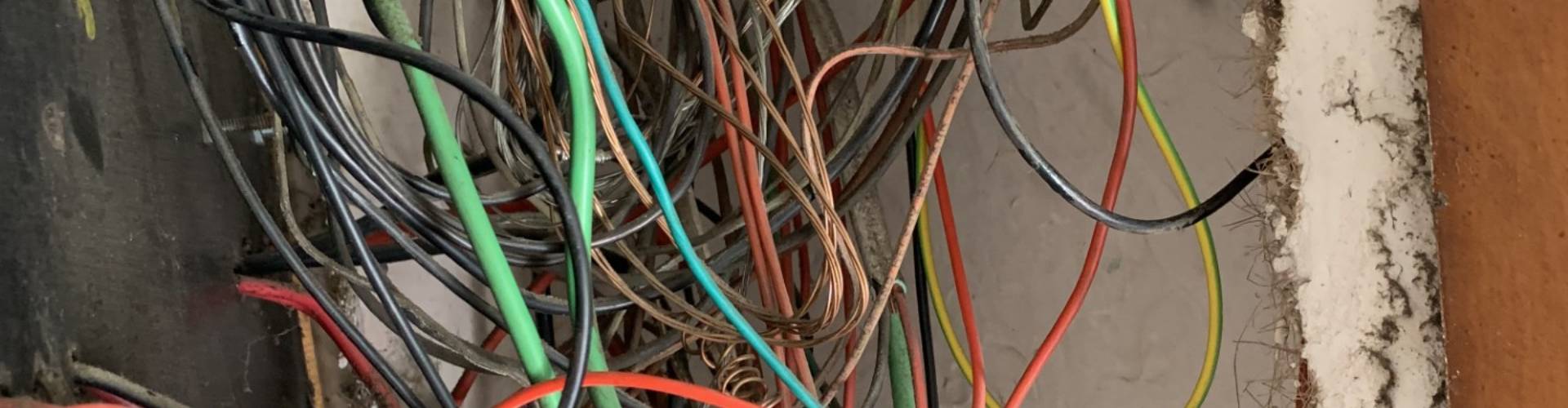 Unsafe deteriorated wiring behind an old fuse board